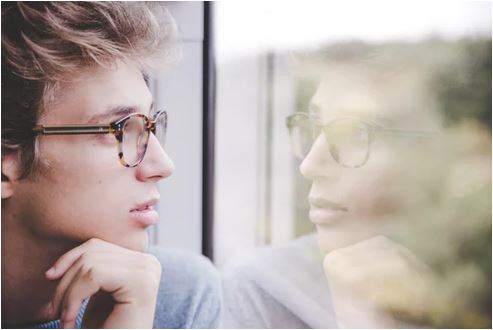 man looking out window and completing his daily reflection