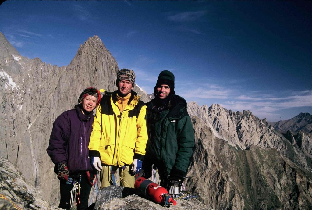 three people celebrate achievements on the summit of the central pyramid in kyrgyzstan
